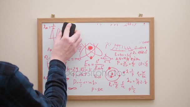 Man erasing formulas, graphs and charts from white board — Stock Video