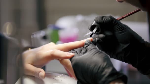 La manicura en el salón de belleza - el maestro cosmético en la máscara médica se ocupa del esmalte en las uñas — Vídeo de stock