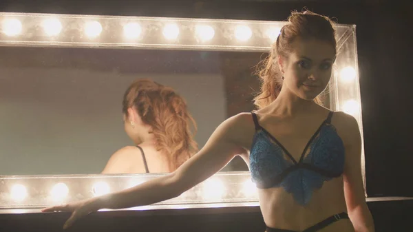 Jonge blonde vrouw in blauw ondergoed te kijken naar spiegel-poseren voor fotograaf — Stockfoto