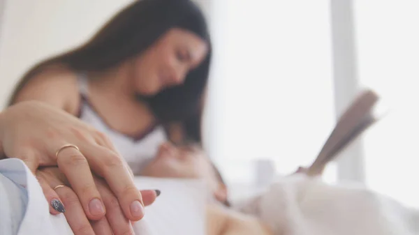 Feliz joven pareja atractiva están juntos en el sofá, la chica lee un libro —  Fotos de Stock