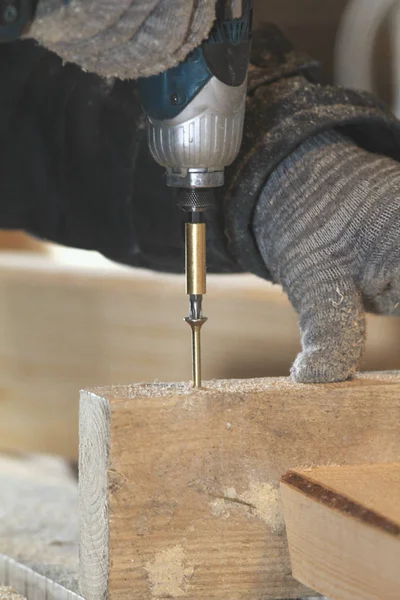 El primer plano de las manos del carpintero atornilla el tornillo en la tabla de madera con el destornillador — Foto de Stock
