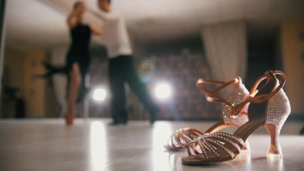 Verschwommene professionelle Tänzer und Tänzerinnen in Kostümen im Studio, Standardschuhe im Vordergrund, Zeitlupe — Stockvideo