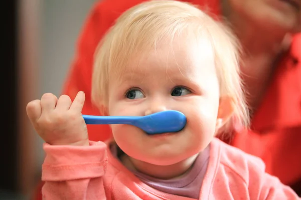 Piccola ragazza dolce bambino con cucchiaio blu durante la colazione — Foto Stock