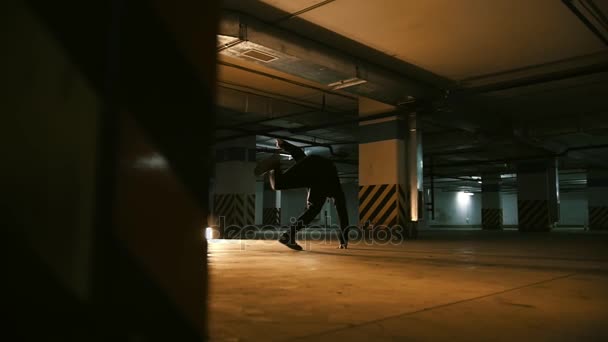 Corredores livres - cara acrobático executa truques no estacionamento subterrâneo - câmera lenta — Vídeo de Stock