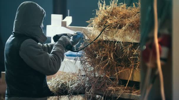 Строитель вкручивает винт в деревянную доску с помощью силовой отвертки - изготавливает строительные блоки из соломы — стоковое видео