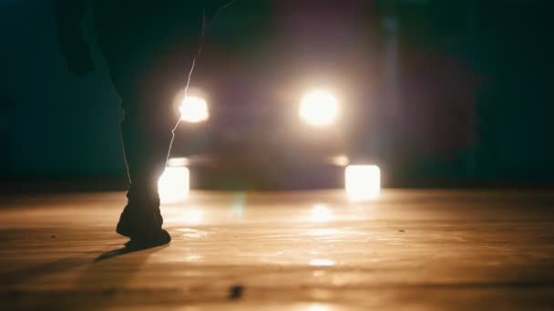 Sylwetka Freerunner młodych stylowe facet robi serie skoków, odwraca się i zamienia się w garażu naprzeciwko reflektory samochodów — Wideo stockowe