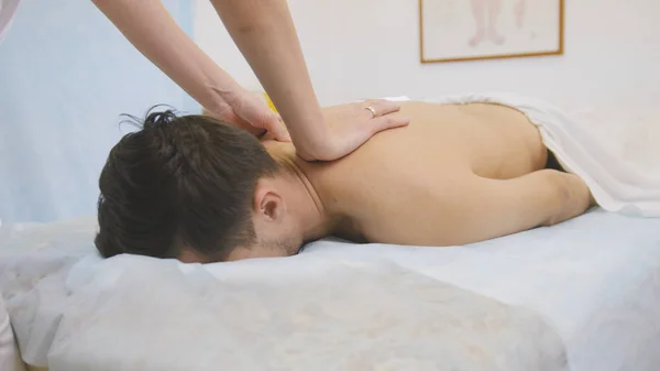 O médico faz massagem nas costas e ombros o homem na fisioterapia — Fotografia de Stock