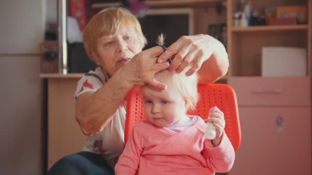 Grandmother with her cute whimper granddaughter, talking and combing — Stock Video