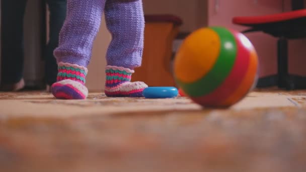 Niñas piernas con sus juguetes, la bola de colores está en primer plano — Vídeos de Stock