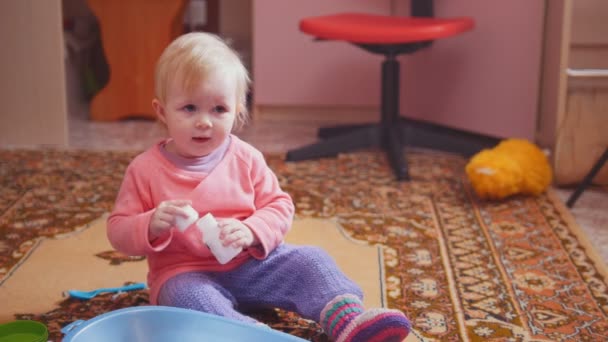 Linda niña jugando con sus juguetes y sonriendo, sentada en el suelo — Vídeos de Stock