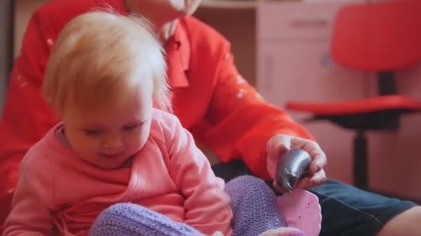 Niña y su abuela jugando juntas sentadas en el suelo, se centran en los juguetes — Vídeos de Stock