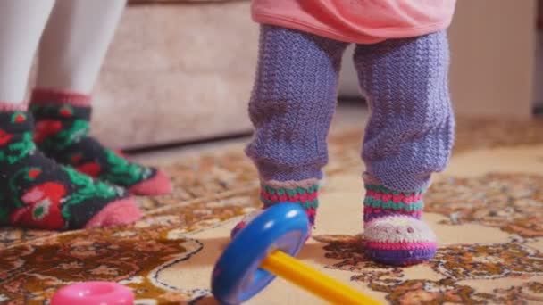 Little girl throwing and collecting the toys, focus on the legs and colored rings — Stock Video