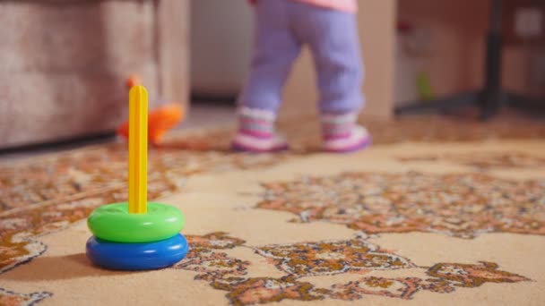 Little girls legs with her toys, the colorful pyramid is in the foreground — Stock Video