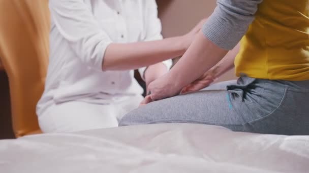 Лікар невролог уважно оглядає пацієнта за допомогою молотка на руках і колінах — стокове відео