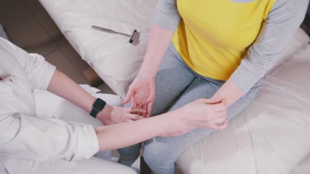 Arzt Neurologe berät und untersucht den Patienten mit einem Metallstab an den Armen und überprüft das Handgelenk, Draufsicht — Stockvideo