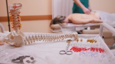 Bastırıyor bel üzerinde bir masaj masanın üzerinde yatan genç bir kadın masaj chiropractor omurga modeli ve uyuşturucu ön planda