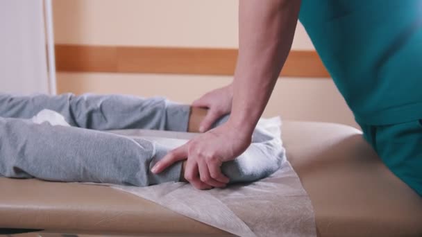 Quiroprático massagear uma mulher deitada em uma mesa de massagem, esticando os pés, close-up das pernas — Vídeo de Stock