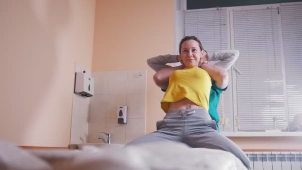 Manual terapeuta massageando e examinando uma jovem mulher esticando a coluna — Vídeo de Stock