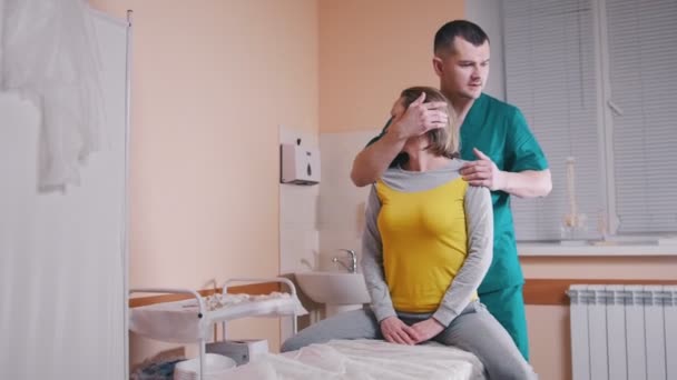 Chiropraktiker massiert eine junge Frau, die sich den Hals verdreht — Stockvideo