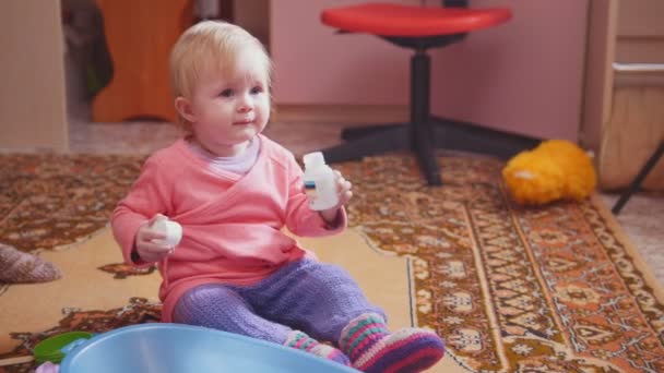 Linda niña jugando con sus juguetes, sentada en el suelo — Vídeo de stock