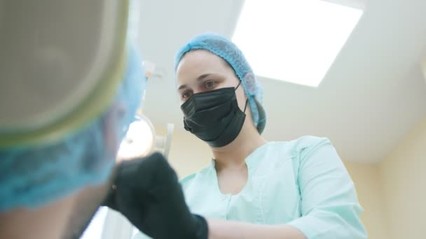 Mujer joven dentista en el trabajo en el consultorio con paciente — Vídeo de stock