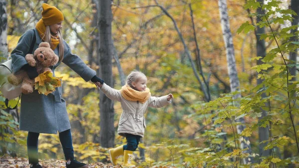 Bonita hija rubia con su mami pasea en el parque de otoño - divertirse y recoger hojas — Foto de Stock