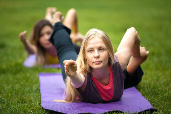 Two young women performs training for flexibility in the park — Stock Photo, Image
