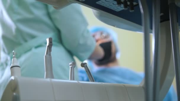 Verschwommener Arzt und Patient in der Zahnarztpraxis, medizinische Instrumente und Bohrer im Vordergrund — Stockvideo