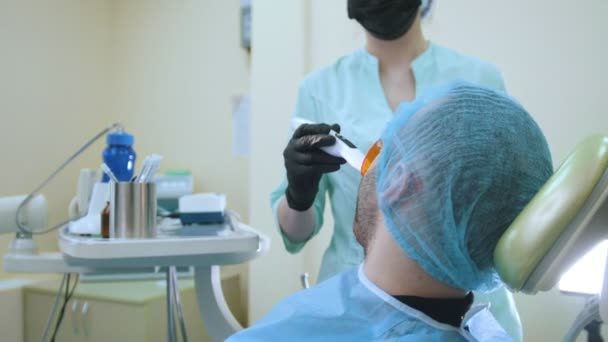 Arzt und Patient in der Zahnarztpraxis, Polymerisation von Füllungen mit Schutzschirm, — Stockvideo