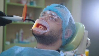 Doktor ve diş ofiste Retraktörü hastayla, ultraviyole ve turuncu koruyucu ekran