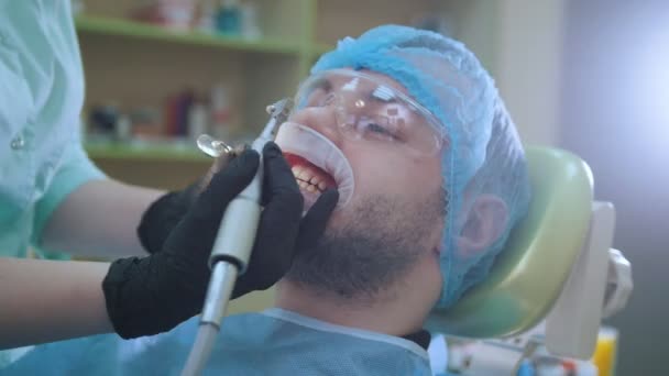 Médico e paciente com dilatador labial no consultório odontológico, polimento com escova — Vídeo de Stock