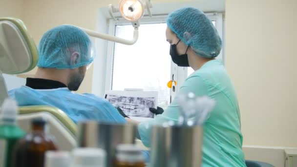 Doktor stomatologist ve danışmanlık, açıklama ve gösteri x-ray hasta diş ofiste, — Stok video