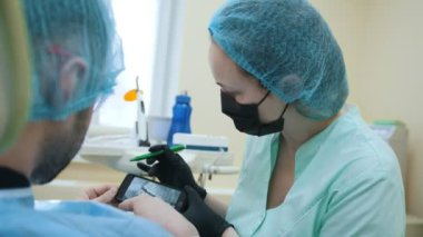 Stomatologist ve diş ofiste, danışmanlık, açıklama ve elektronik cihazların dijital x-ışını kullanarak gösterilen hasta