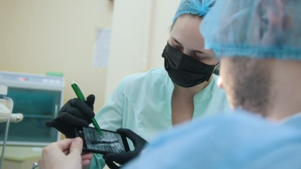 Stomatologist en patiënt in de tandheelkundige kantoor, consulting, uitleg en demonstratie van het gebruik van de x-ray van elektronische apparaten — Stockvideo