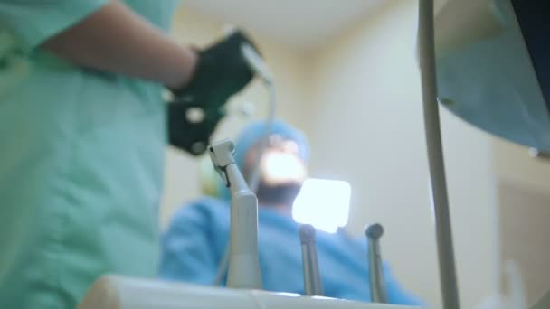 Doctor and patient in the dental office, treatment process, equipment and tooling in the foreground — Stock Video