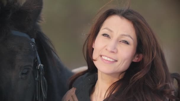 Hermosa jinete mujer joven y su caballo negro en el bosque nevado — Vídeos de Stock