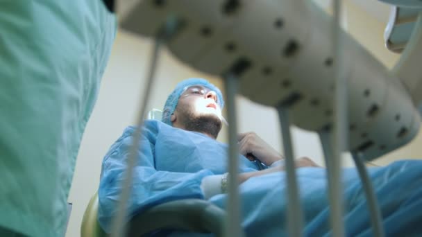 Médico y paciente en el consultorio dental, proceso de tratamiento, equipo en primer plano — Vídeo de stock