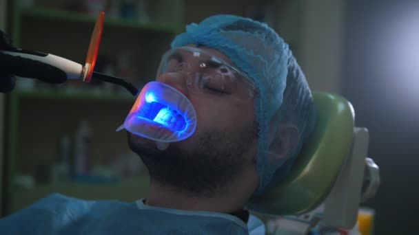Doctor and patient with lip dilator in the dental office, cleaning and disinfection with ultraviolet light and orange protective screen — Stock Video