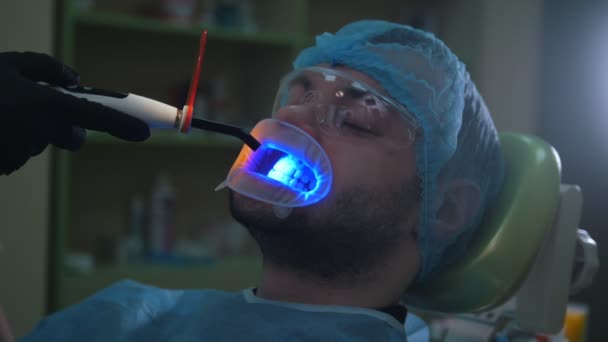 Médico y paciente con dilatador labial en consultorio dental, limpieza con luz ultravioleta y pantalla protectora naranja — Vídeo de stock