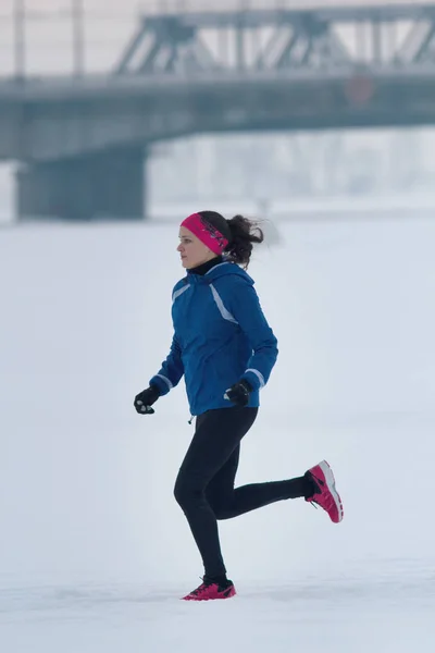 Młodych kobiet sportowiec uruchomiona pilnie w zimie po śniegu — Zdjęcie stockowe