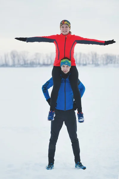 Portret dwóch uśmiechający się młodych sportowców w zimie, dziewczyna siedzi na ramionach faceta — Zdjęcie stockowe