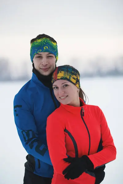 Porträtt av par - två skrattande unga idrottsmän vintertid is fält — Stockfoto