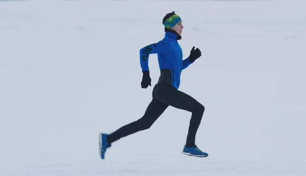 Jonge mannelijke atleet lopen snel in de winter door de besneeuwde ice-veld — Stockfoto