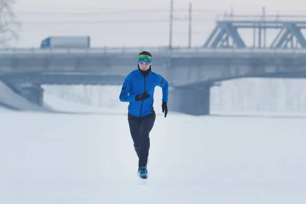 Ung manlig idrottsman som kör på vintern i snön — Stockfoto