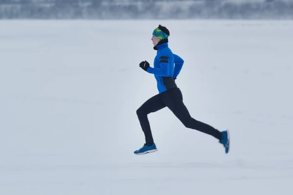 Mannelijke atleet loopt in de winter door de sneeuw — Stockfoto
