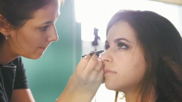 El proceso del maquillaje en el salón de belleza para la mujer joven de cabello negro - haciendo el rostro para los ojos — Vídeo de stock