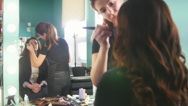 Styliste professionnel femme faisant maquillage pour jeune femme devant le miroir dans le salon de beauté — Video