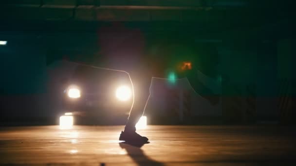 Silhueta de um jovem freerunner fazendo saltos acrobáticos no estacionamento subterrâneo, câmera lenta — Vídeo de Stock