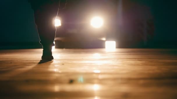 Silhouette eines Mannes, der in der Garage vor Scheinwerfern vorwärts geht - Füße aus nächster Nähe — Stockvideo