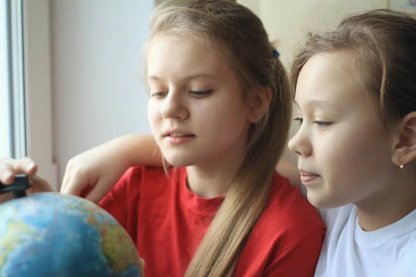 Due adolescenti ragazze sorelle a casa guardando il globo — Foto Stock